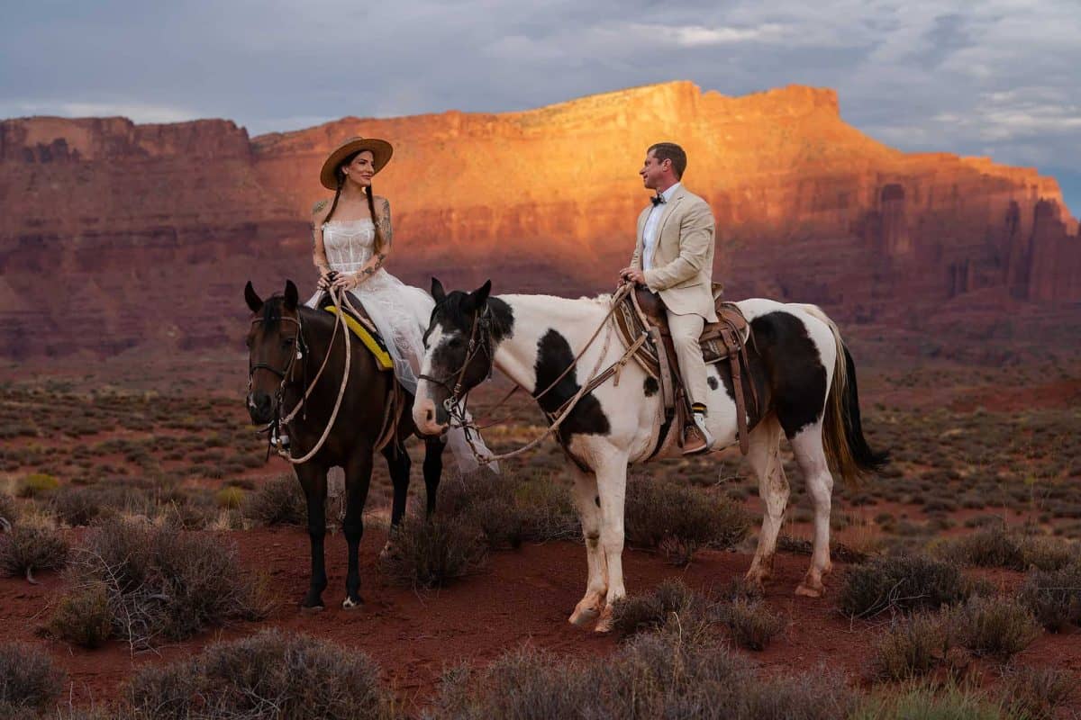 Bride and groom ride horses throughout the red rocks in Moab during their elopement | Moab Adventure Elopement with Arches, Pizza, and Horses | Mountain Made Photography | Zion Brides Feature