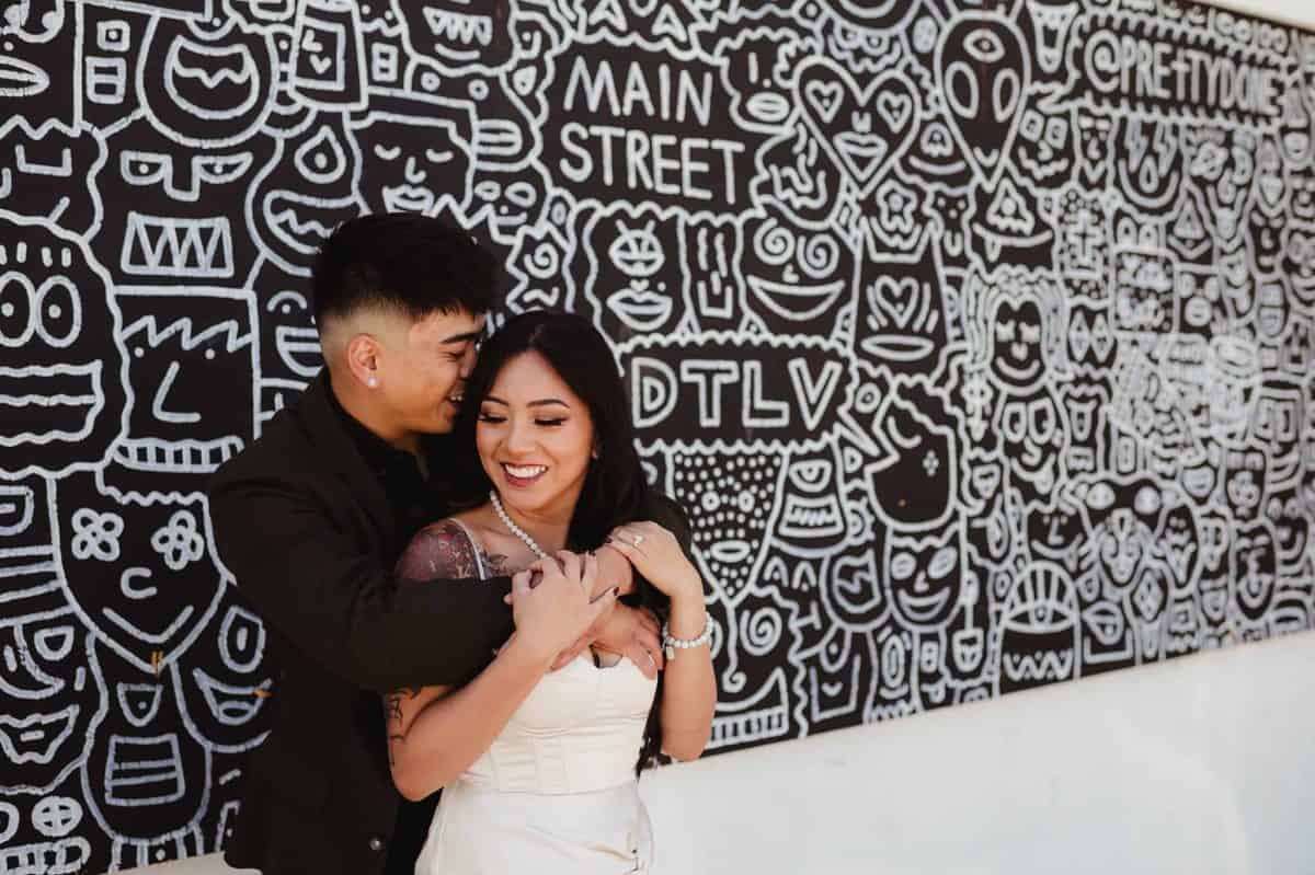 Couple standing against a white and black graffiti wall in Vegas | Las Vegas Engagement Session at the Velveteen Rabbit | Amber Garrett Photography | Adventure Wed Feature
