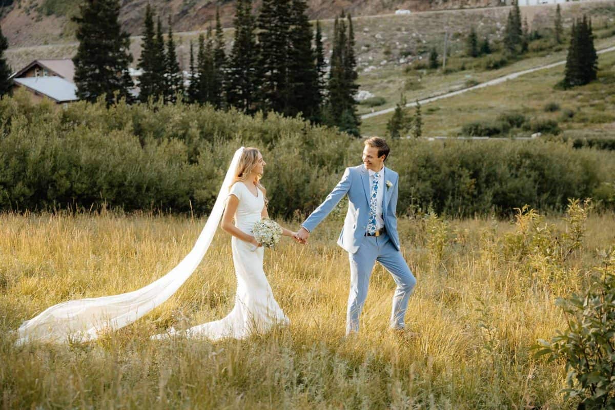 Groom in powder blue suit with blue floral tie, bride in classic white dress and veil with white floral wildflower bouquet | Alta Utah Summer Wedding Formal Session | Kae D Photography | Adventure Wed Feature