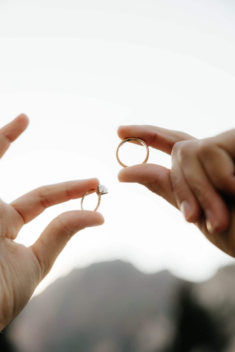 Alta Utah Summer Wedding Formal Session Bride and groom hold wedding rings up to the sky | Alta Utah Summer Wedding Formal Session | Kae D Photography | Adventure Wed Feature