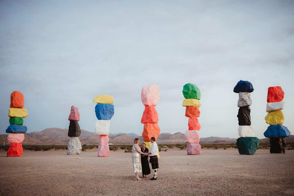Couple at Seven Magic Mountains in Nevada having a ceremony with seven magoic mountains at sunrise | Personal Sunrise Elopement At Seven Magic Mountains | Amber Garrett Photography | Adventure Wed feature